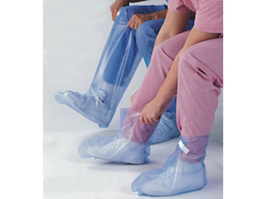 Two people wearing scrubs and protective shoe covers; one person is pulling a transparent blue cover over their shoe.